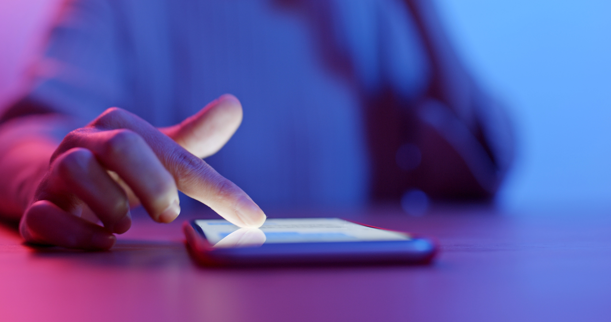 A hand scrolls on a digital device at night