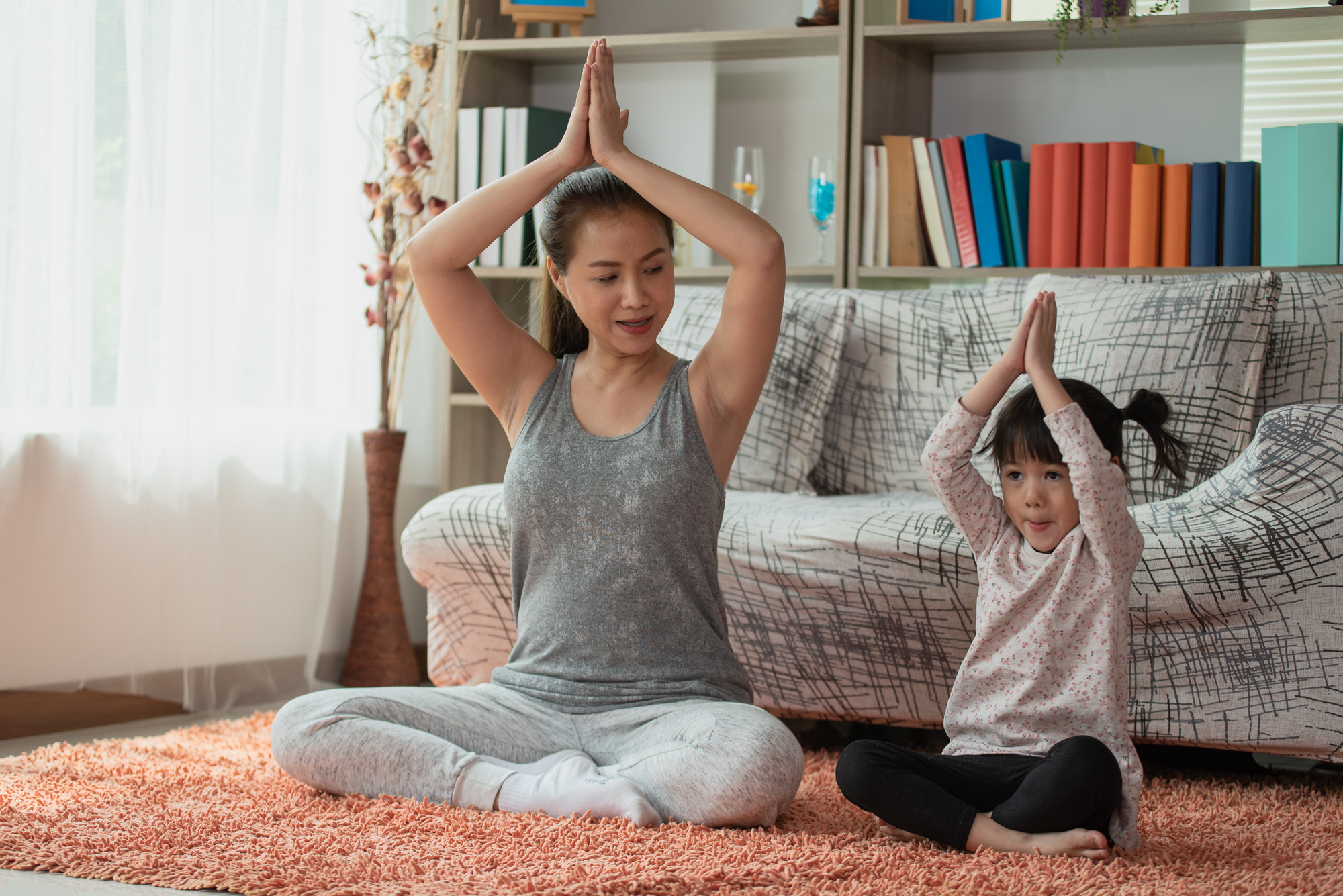 a mom and daughter sit in a yoga pose 