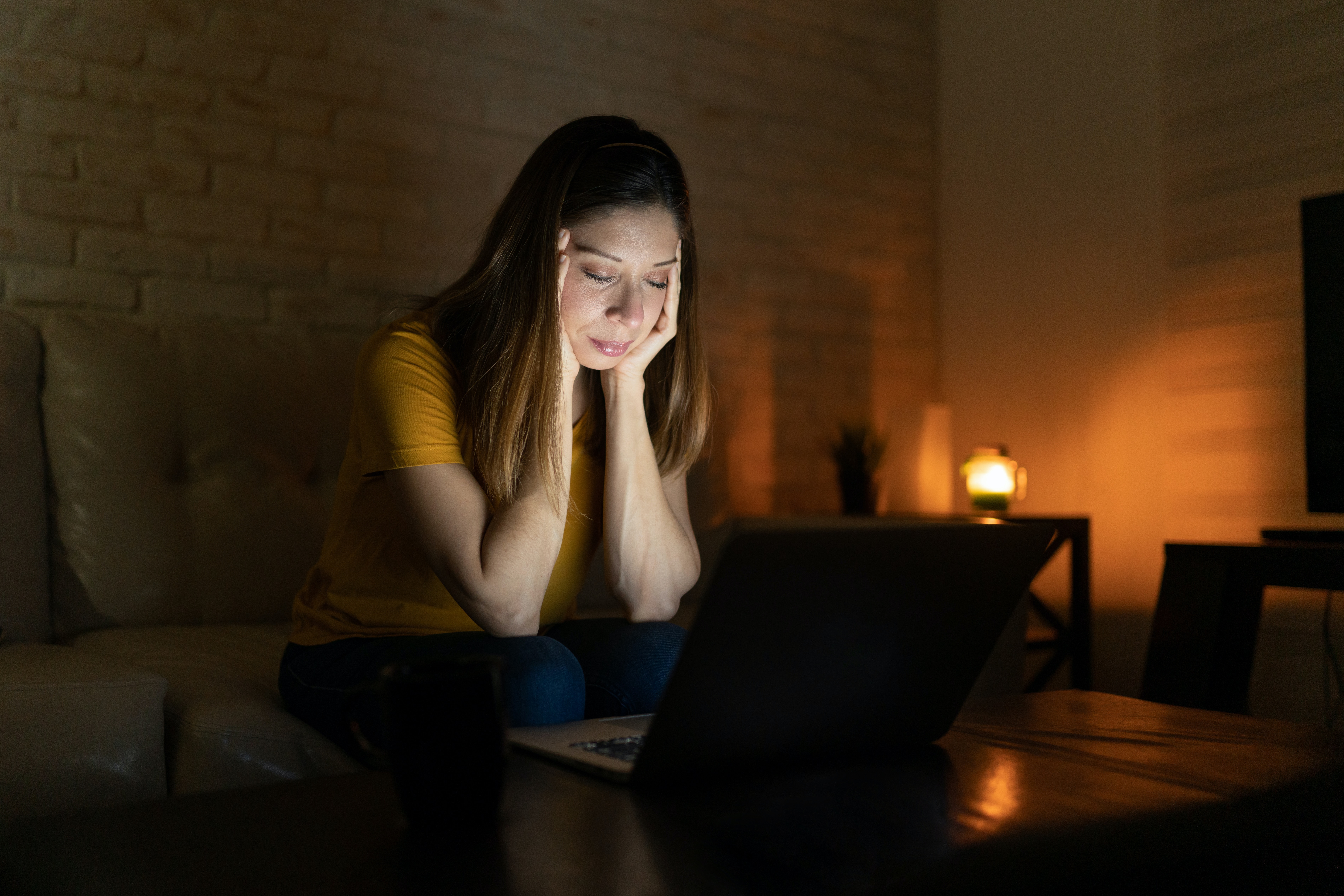  woman feeling overwhelmed at night while working on a laptop computer