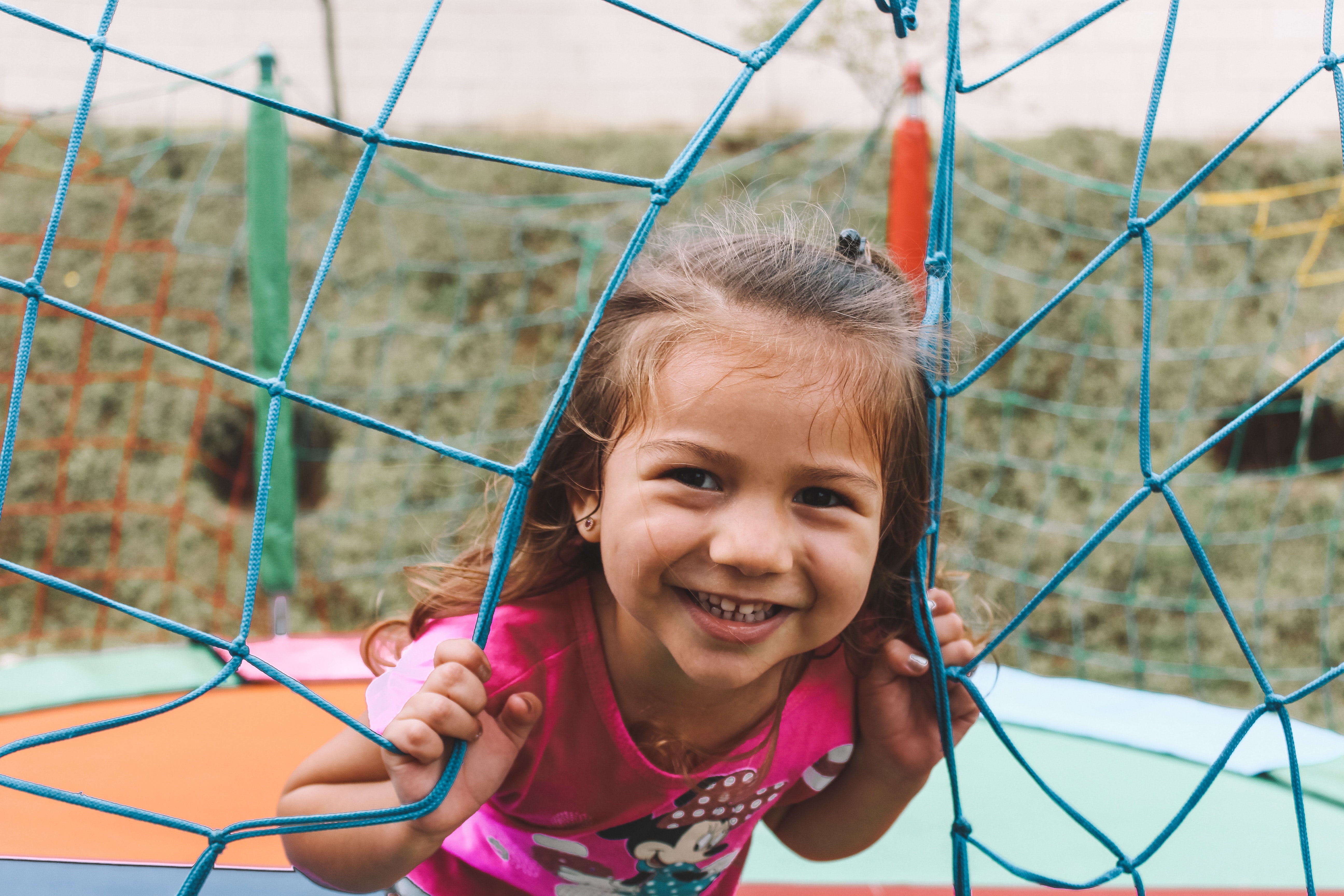a little girl playing on a jungle gym, smiling at the camera