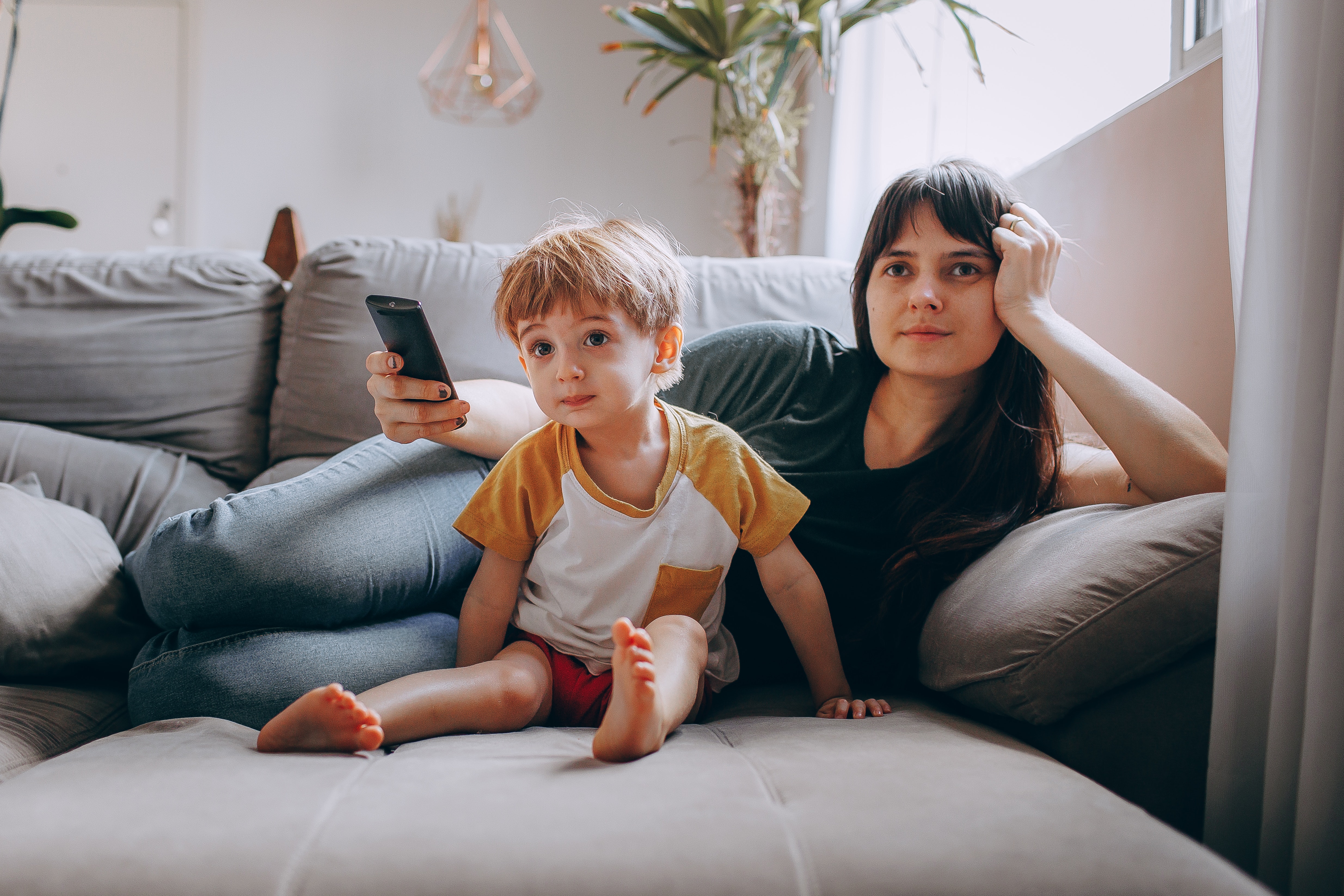 A mother and son on the couch watching TV