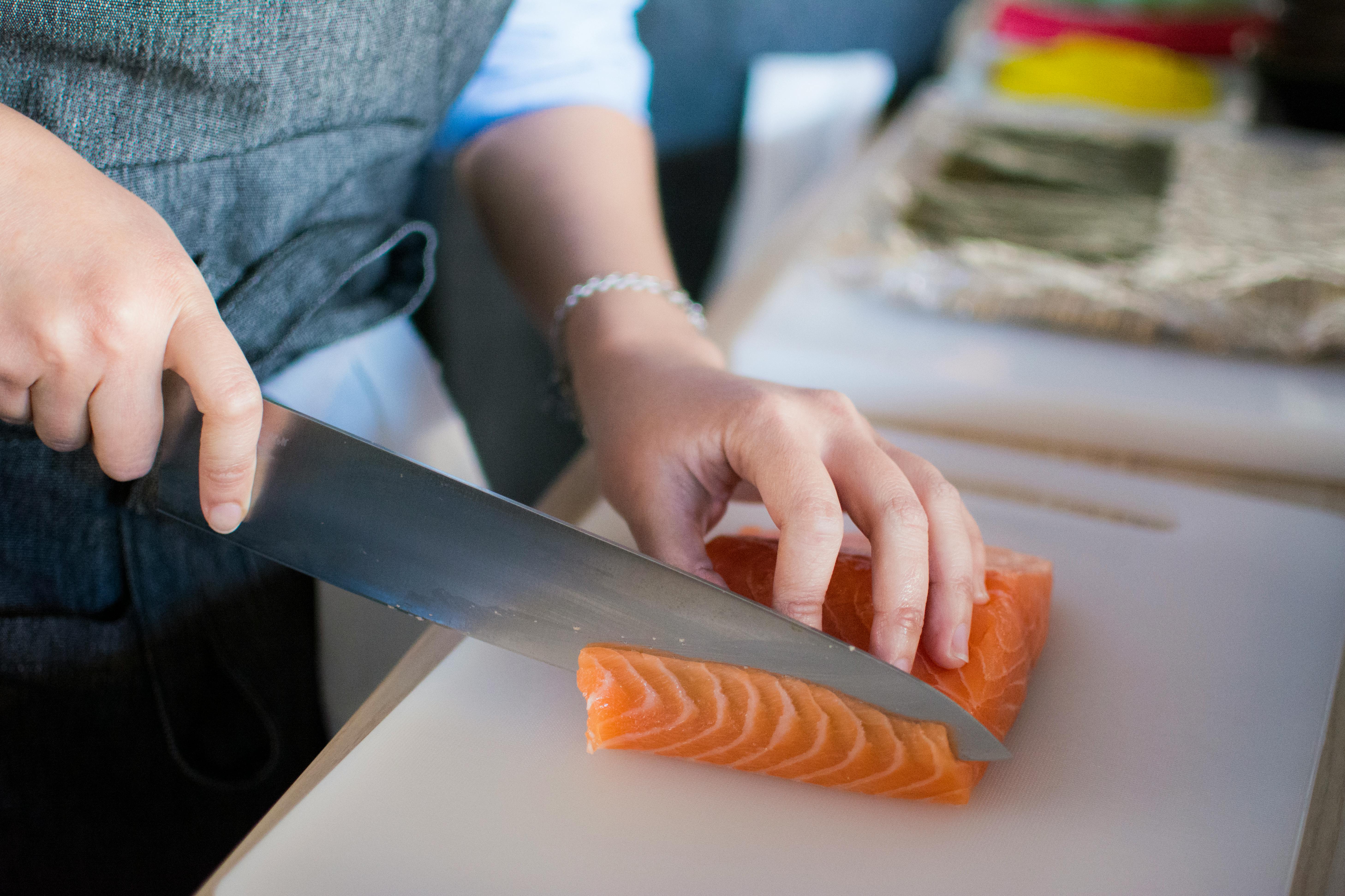 A hand cuts up salmon