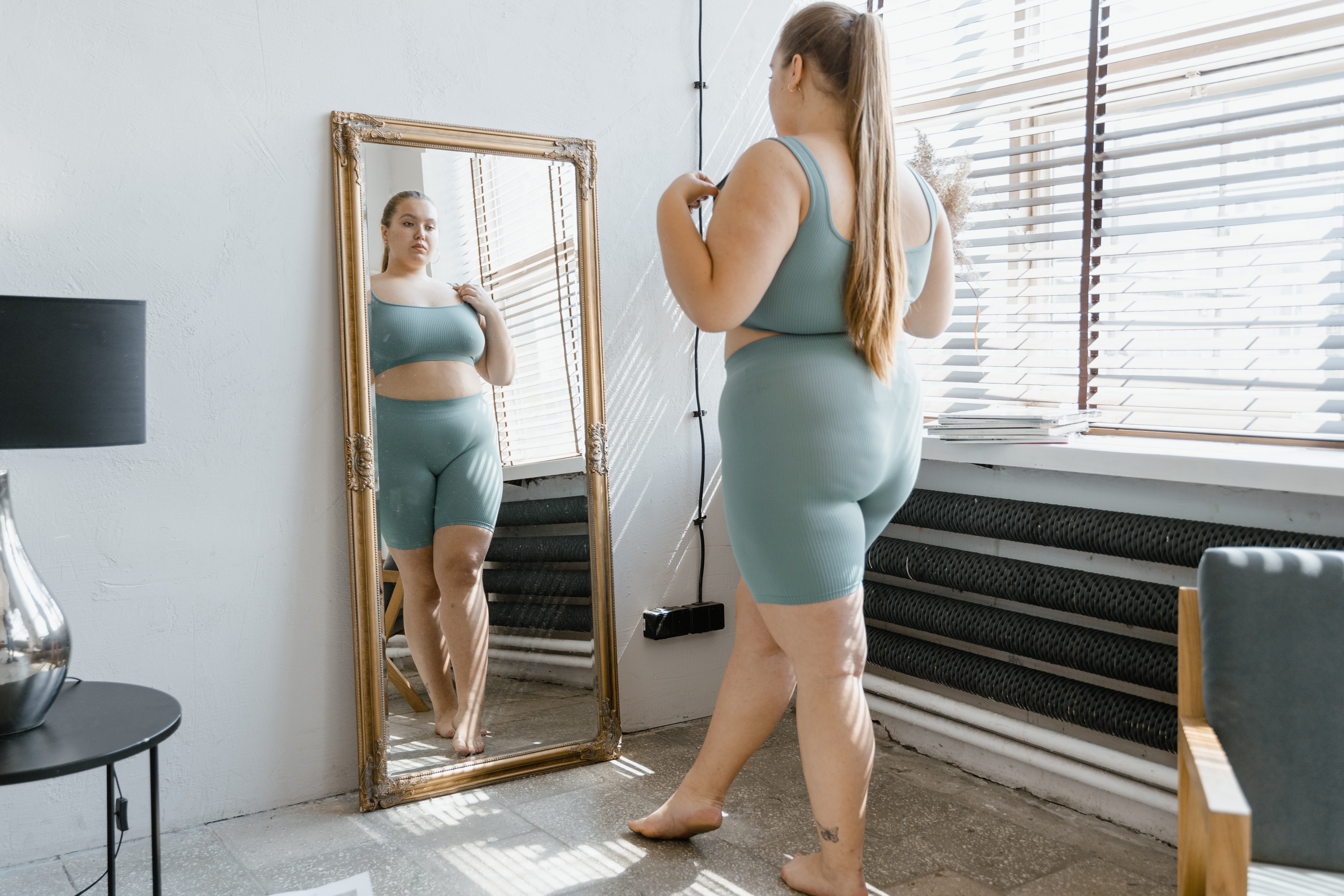 woman looking at her body in a mirror