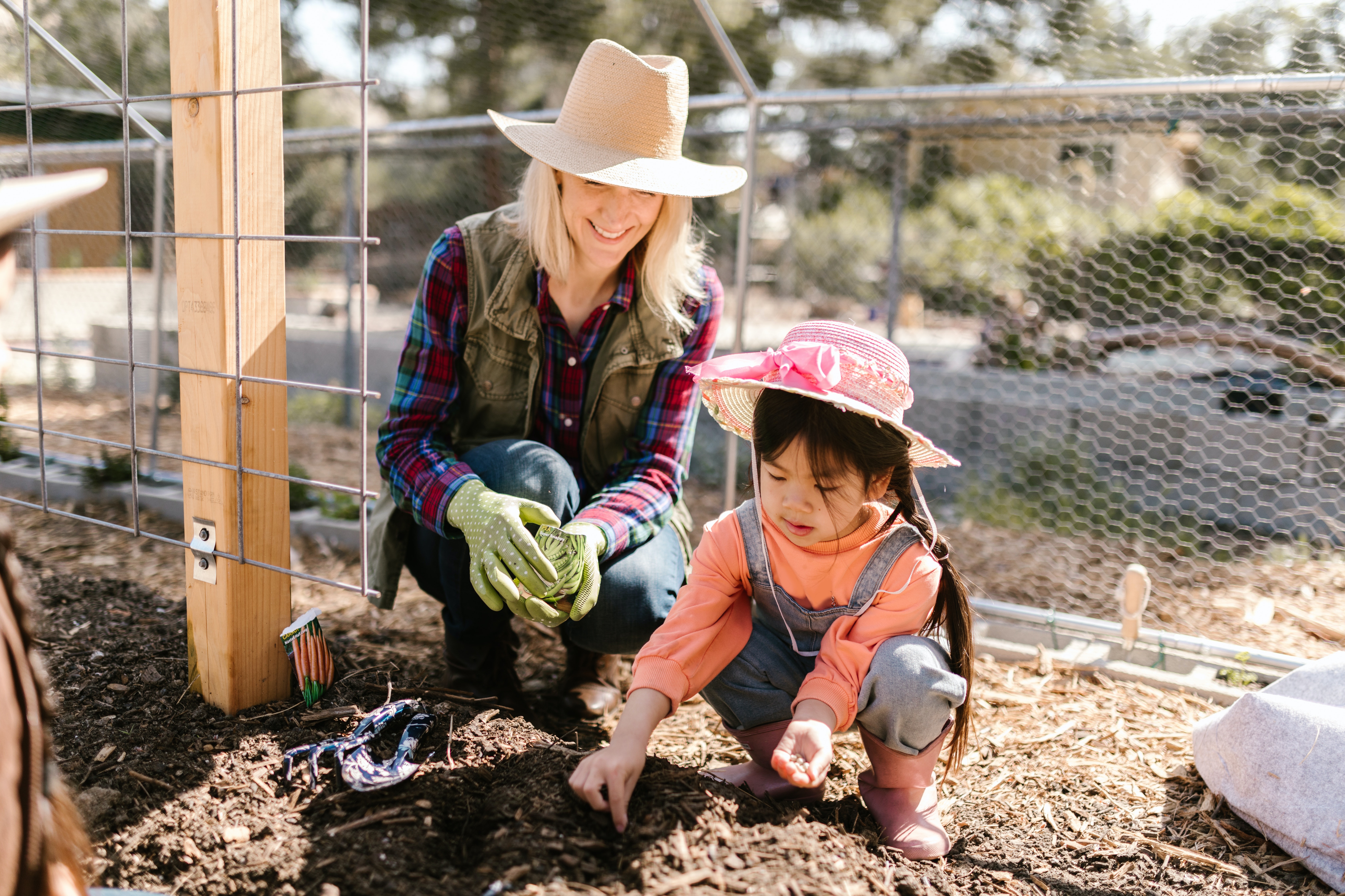 a mother and daughter planting seeds outside 