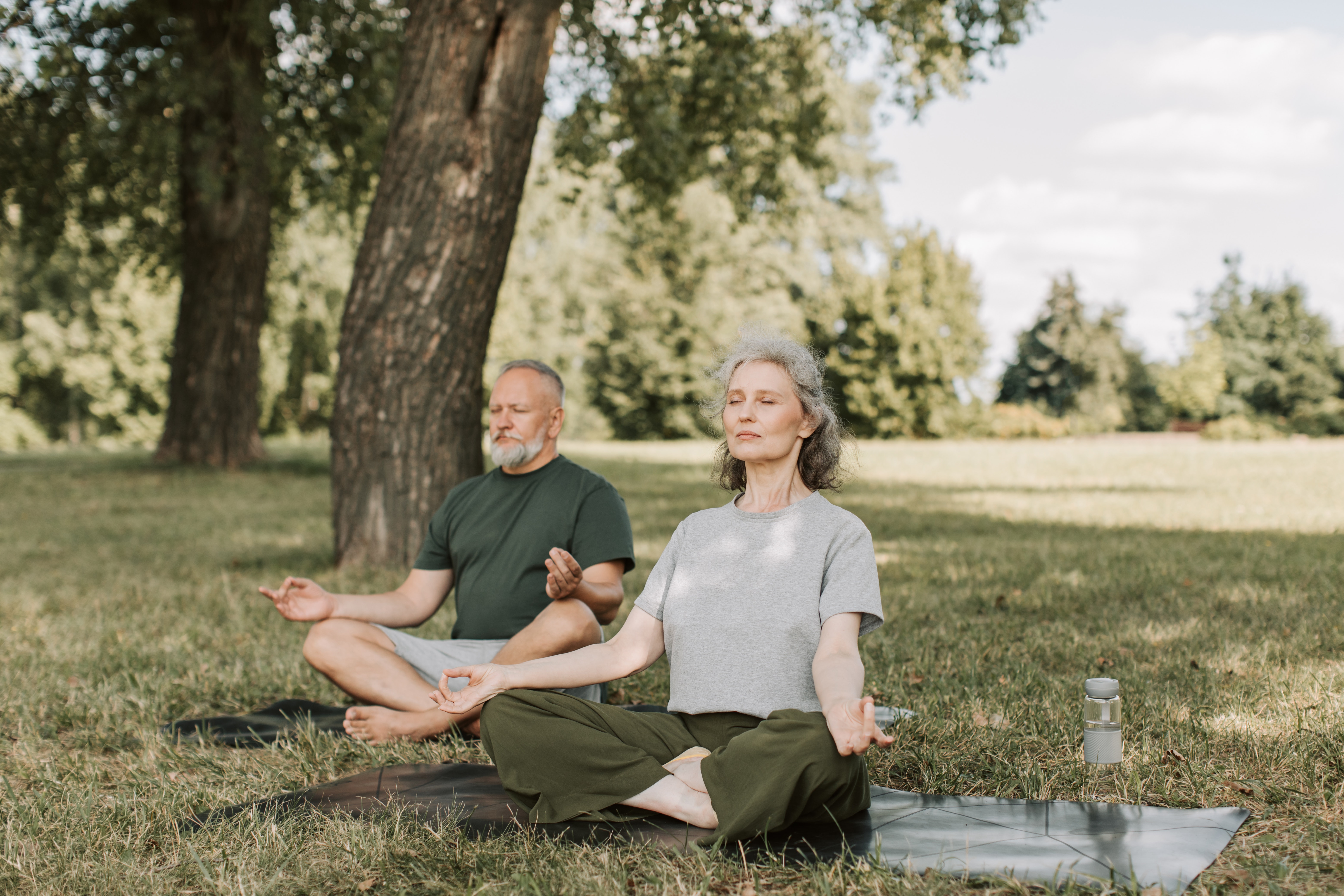 older man and woman on yoga mats meditating