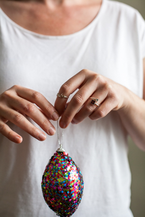 hands with Tribe Of Lamb rings, holding ornament