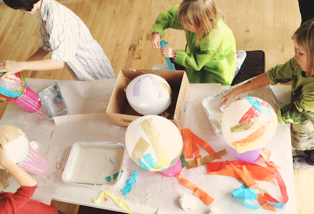 Kids applying paper to balloons during lantern-making