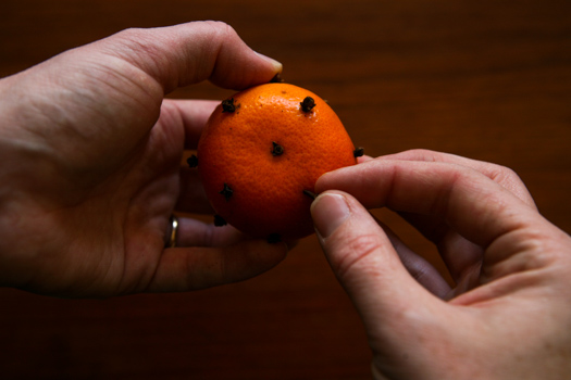 close up of inserting clove into tangerine