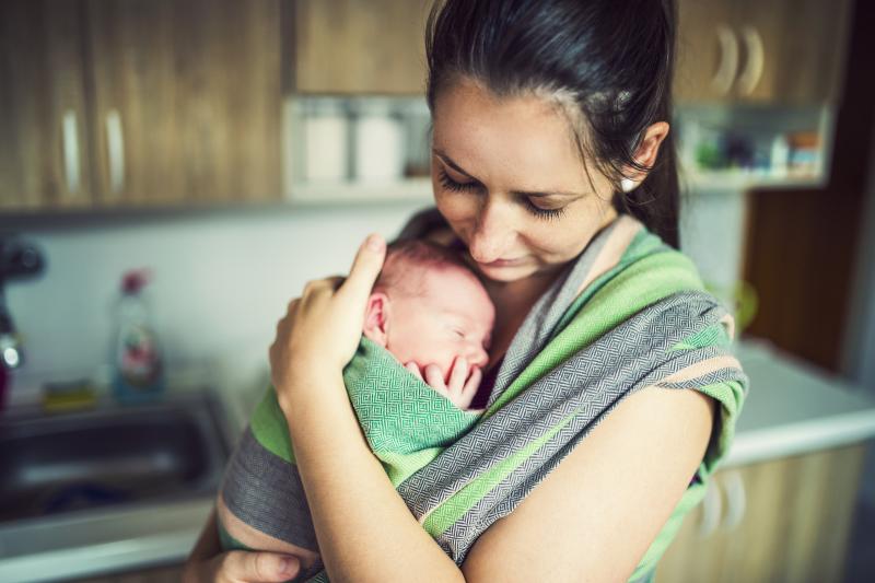 Baby Carrier Selection for Beginners: mom holding newborn in sling carrier