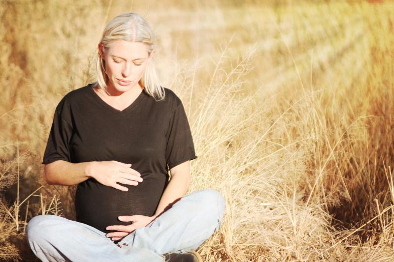 pregnant woman sitting in grassy meadow
