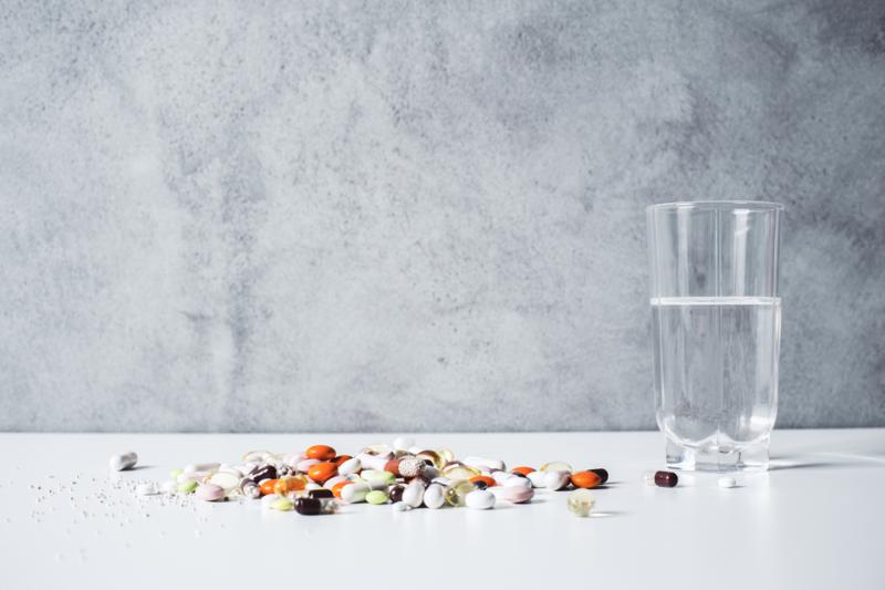 assortment of vitamins and supplements on a table next to a glass of water