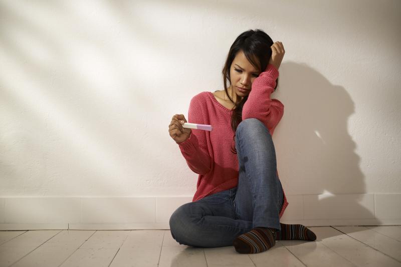 woman looking anxiously at a pregnancy test stick