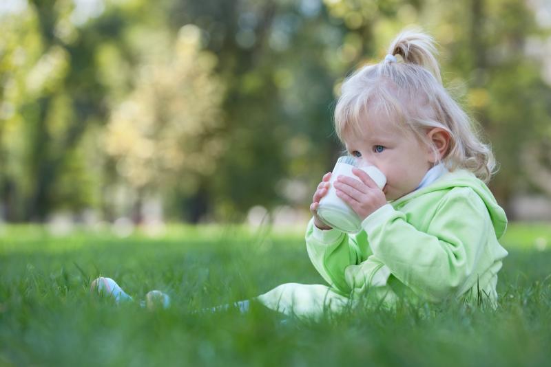 very young toddler drinking milk from a cup
