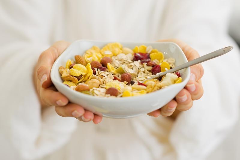 A white cereal bowl with corn flakes and berries 