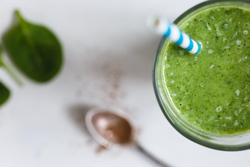 5 Smoothie Moves for Smart Parents Photo of a green smoothie with a straw and spinach leaves scattered around it