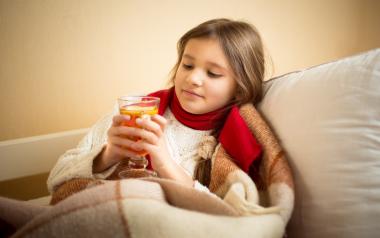 little girl drinking tea covered up with blanket