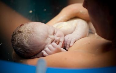A Guide to Taking Care of the Perineum After Birth: newborn baby on mom's chest in birthing pool