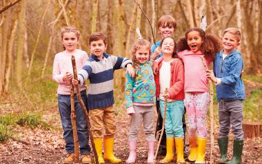 seven children wearing rubber boots playing in the woods