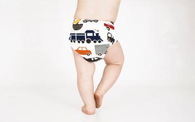 view of toddler from the middle of back down wearing cloth diaper with vehicle pattern