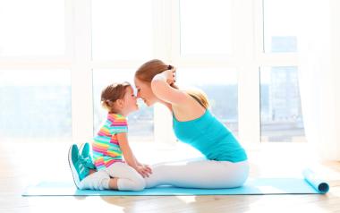 mom doing sit-ups while her child sits on her legs