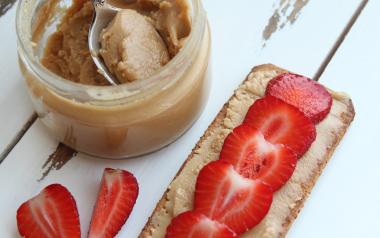 jar of nut butter beside bread and strawberries