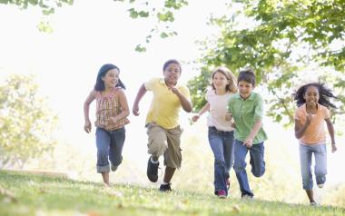 five kids running through grass toward camera
