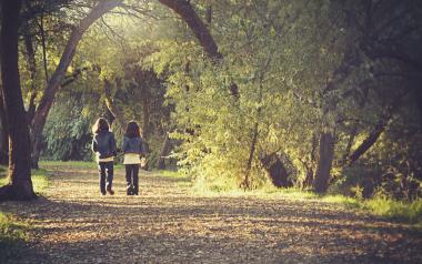 two kids walking along a path in a wooded park
