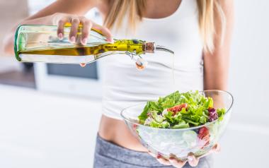 woman pouring olive oil on her salad