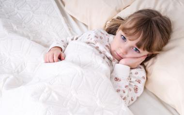child lying in bed looking distressed
