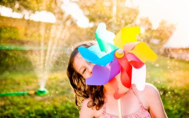 young girl peeking out from behind a whirligig