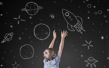 young child observing chalkboard drawings of space