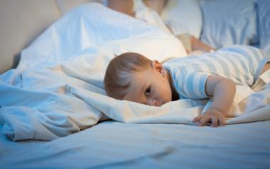 infant lying awake in parent's bed