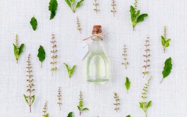 herbs surrounding a bottle of essential oil