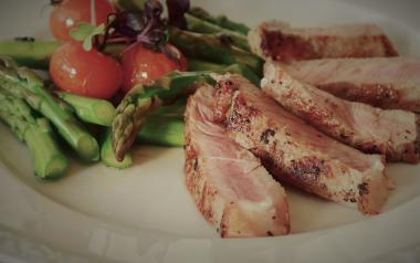 roasted meat, asparagus and tomatoes on a plate