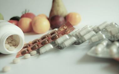 vitamin supplements with fruit in the background