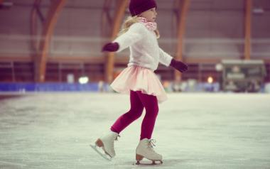 little girl skating in a red cap, warm gloves and sweater