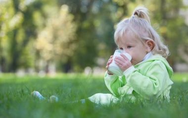 very young toddler drinking milk from a cup