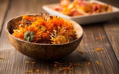 Dried yellow flower buds from the herb calendula. The dried flowers are in a small bowl.