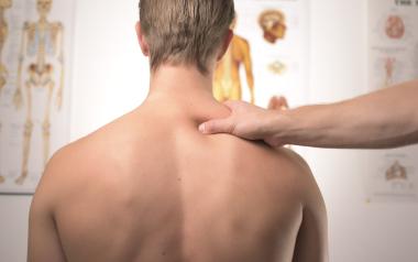 A chiropractor places a hand on the shoulder of a man