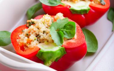 A red pepper stuffed with quinoa on a baking dish.