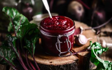 A deep red, beet dip in a mason jar with a spoon sticking out.