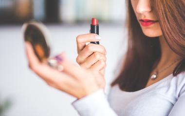 woman applies lipstick in mirror