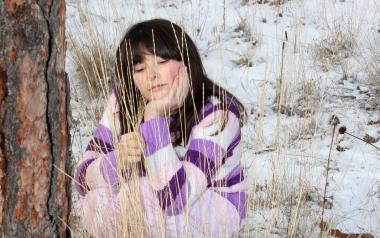 a woman sits in a wintry landscape and looks thoughtfully at a patch of grass 