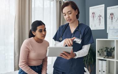 female doctor talking to female patient while looking at folder 
