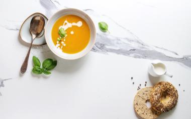 carrot soup in a bowl, a spoon and an everything bagel