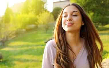 woman outside taking a deep breath in with eyes closed