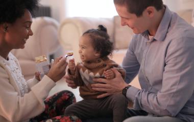 mother feeding toddler while father is holding the toddler