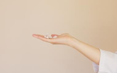 a hand holding white pills 