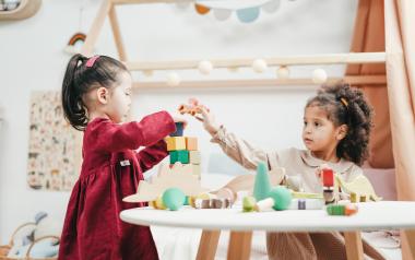 two little girls playing with blocks at a table