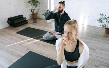 man and woman on yoga mats doing alternating nostril breathing exercise